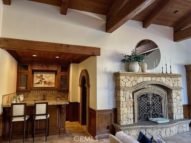 bar featuring a fireplace, decorative backsplash, beam ceiling, and wood ceiling