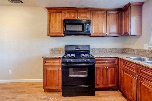 kitchen with light wood-type flooring, sink, and black appliances