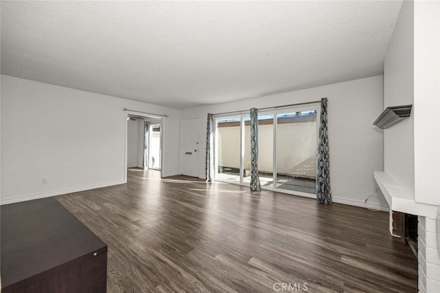 unfurnished living room with dark hardwood / wood-style flooring, a wealth of natural light, and a textured ceiling