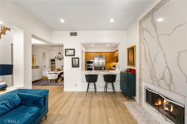 living room featuring a high end fireplace and light hardwood / wood-style flooring