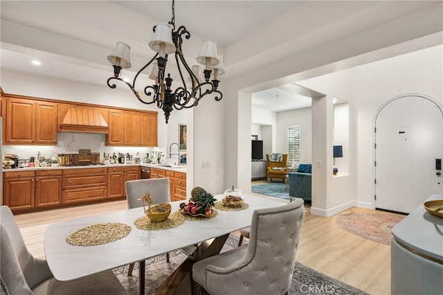 kitchen with an inviting chandelier, premium range hood, decorative backsplash, hanging light fixtures, and light hardwood / wood-style flooring