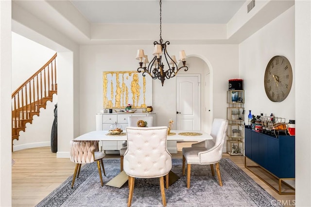 dining space with an inviting chandelier, a tray ceiling, and hardwood / wood-style floors