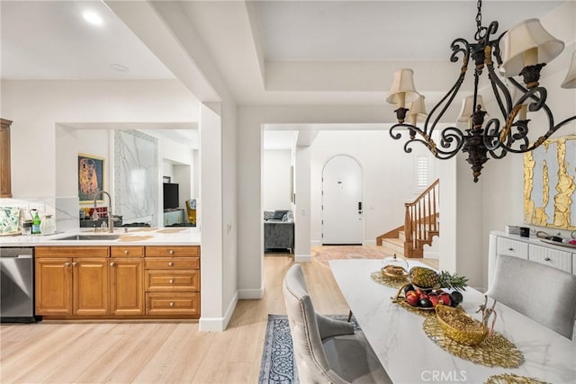 kitchen with sink, dishwasher, a chandelier, and light hardwood / wood-style flooring