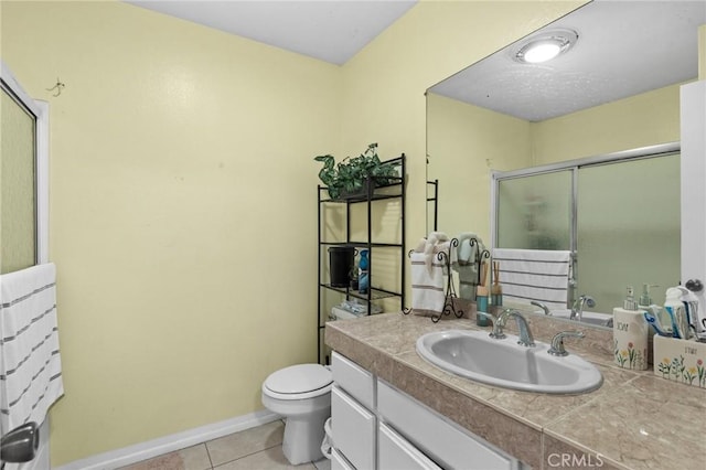 bathroom featuring tile patterned floors, vanity, toilet, and walk in shower