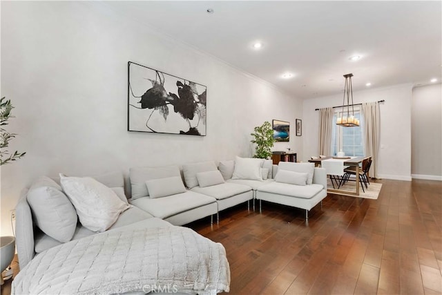 living room with dark hardwood / wood-style floors, ornamental molding, and a notable chandelier