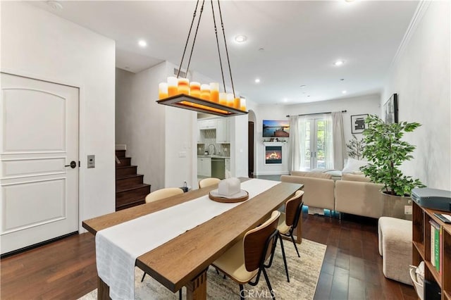 dining area featuring dark wood-type flooring, sink, and ornamental molding