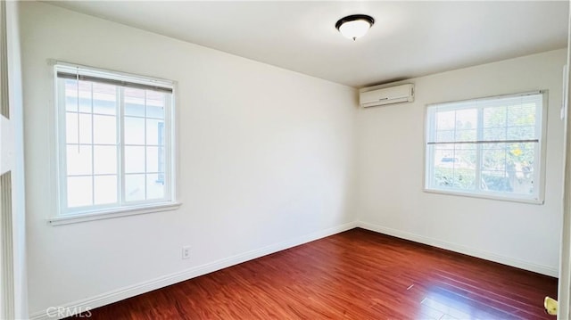 empty room with an AC wall unit, dark wood-type flooring, and a wealth of natural light