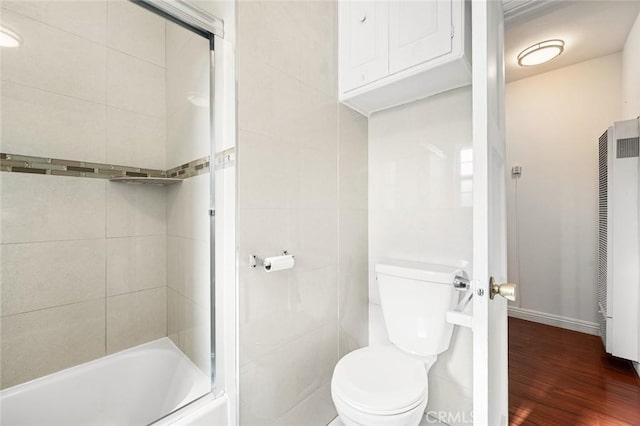 bathroom featuring hardwood / wood-style floors, tiled shower / bath combo, and toilet