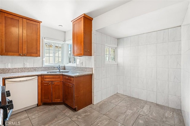 kitchen with stove, sink, tile walls, and white dishwasher