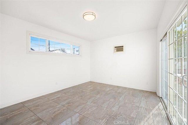 spare room featuring a wall unit AC and a healthy amount of sunlight