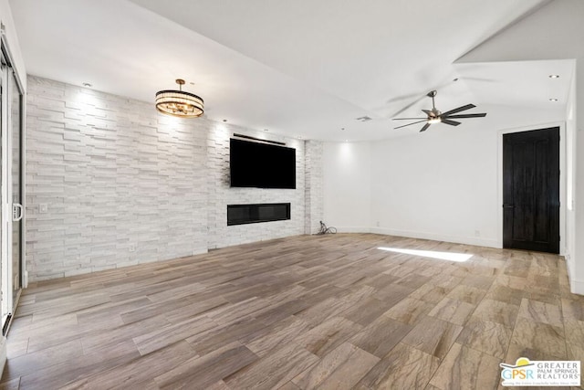 unfurnished living room featuring ceiling fan and a stone fireplace