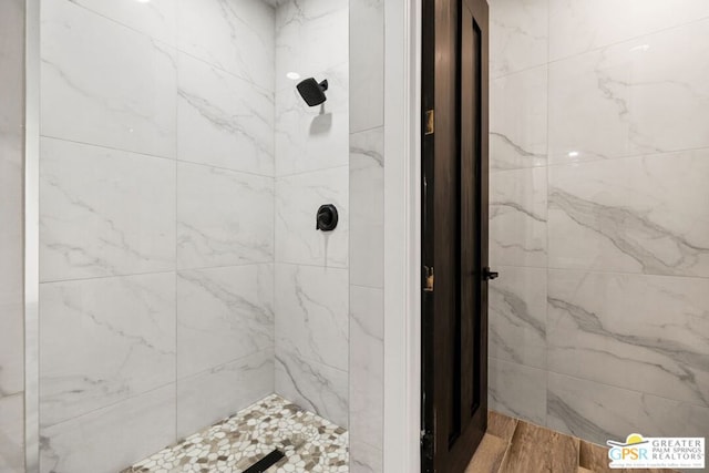 bathroom with wood-type flooring and tiled shower