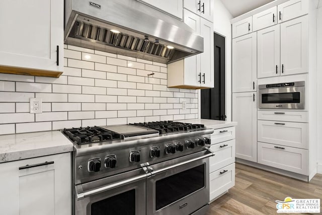 kitchen with extractor fan, white cabinetry, light stone counters, double oven range, and backsplash