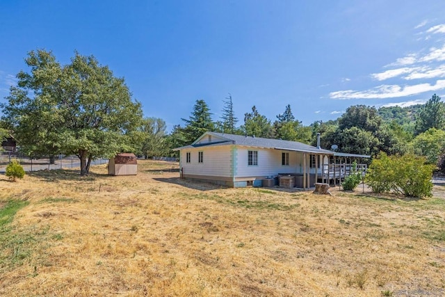 exterior space featuring a wooden deck, a storage shed, and a lawn