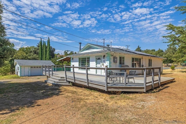 rear view of house featuring a garage, an outdoor structure, and a deck