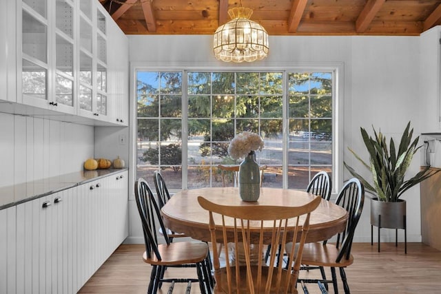 dining area with beamed ceiling, a notable chandelier, wood ceiling, and light hardwood / wood-style flooring