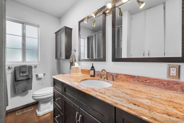 bathroom featuring wood-type flooring, toilet, and vanity