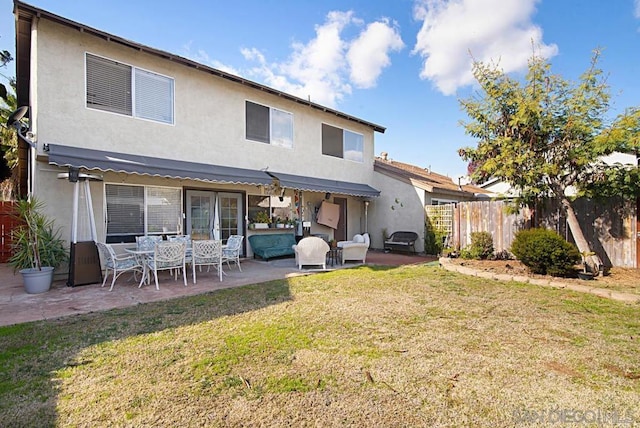 back of property with a lawn and a patio area