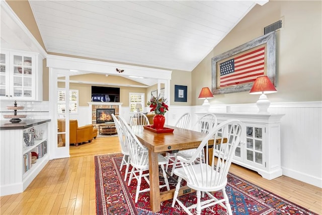 dining space featuring vaulted ceiling, wood ceiling, and light hardwood / wood-style flooring