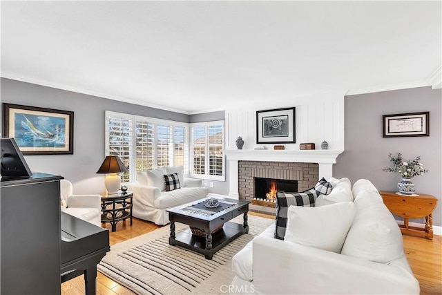 living room with a brick fireplace, ornamental molding, and light hardwood / wood-style flooring