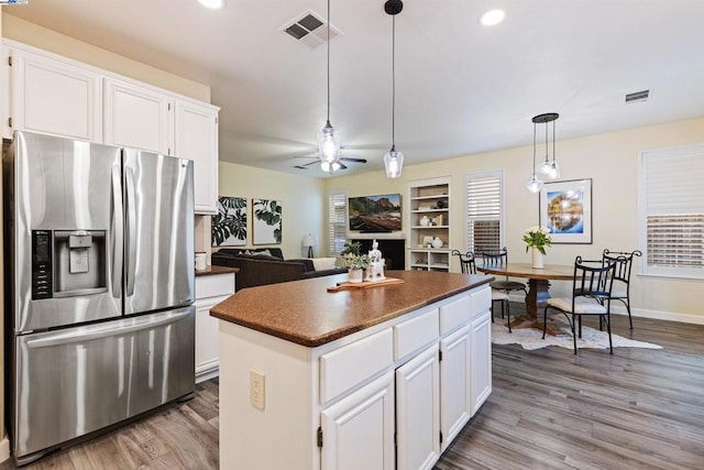 kitchen with stainless steel refrigerator with ice dispenser, pendant lighting, white cabinets, and a kitchen island