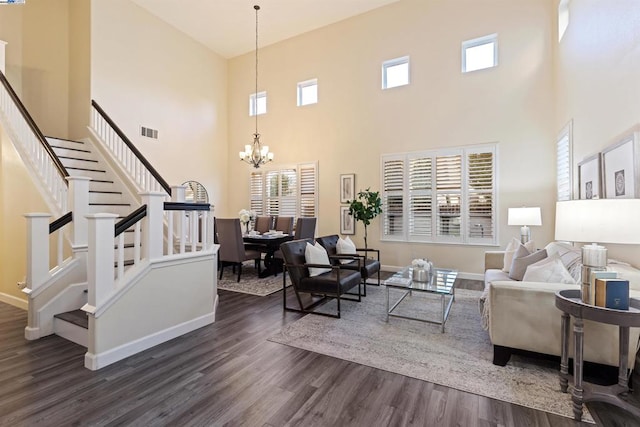 living room featuring dark wood-type flooring, a chandelier, a towering ceiling, and plenty of natural light