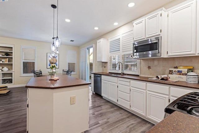 kitchen with white cabinets, a center island, decorative light fixtures, stainless steel appliances, and sink