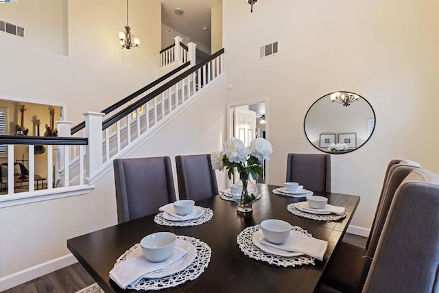 dining room featuring an inviting chandelier, a towering ceiling, and hardwood / wood-style floors