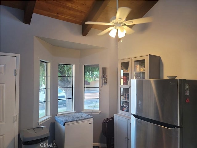 kitchen with wood ceiling, stainless steel refrigerator, light stone countertops, a wealth of natural light, and beamed ceiling