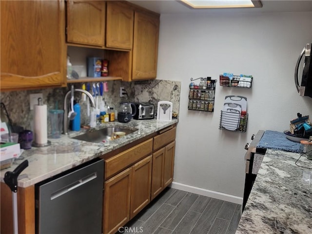 kitchen featuring stainless steel appliances, backsplash, light stone counters, and sink