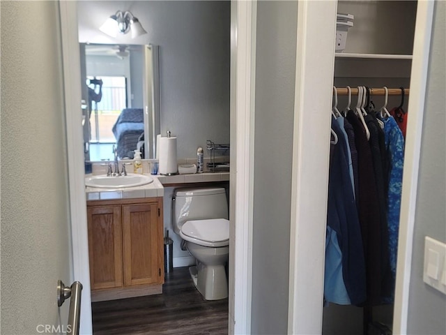 bathroom with toilet, hardwood / wood-style floors, and vanity