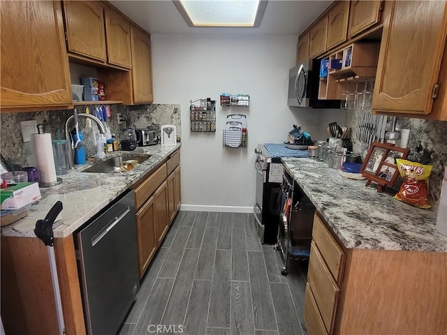 kitchen with light stone countertops, sink, backsplash, and appliances with stainless steel finishes