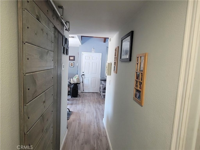 hallway with a barn door and light wood-type flooring