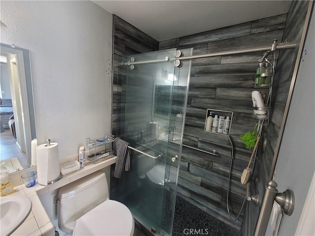 bathroom featuring a shower with shower door, toilet, and vanity