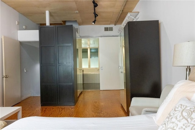 bedroom featuring hardwood / wood-style floors and track lighting