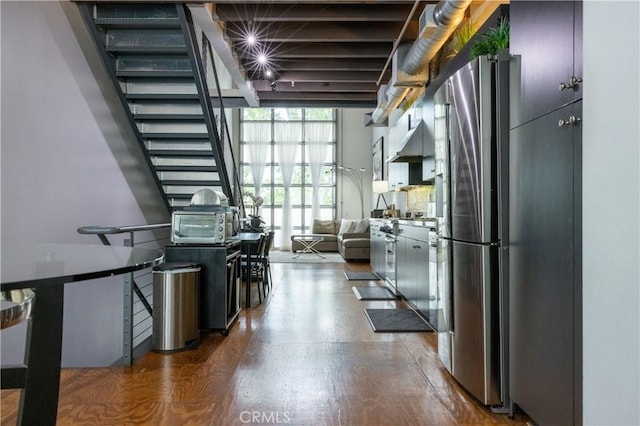 kitchen featuring a wall of windows, wood-type flooring, and stainless steel refrigerator