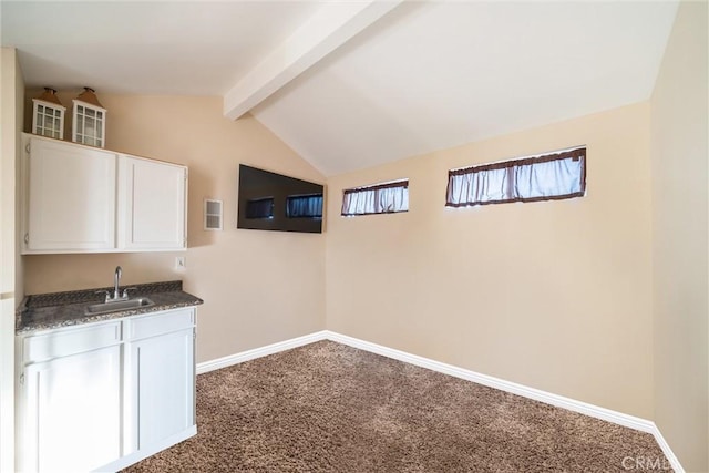 bar featuring vaulted ceiling with beams, dark carpet, sink, and white cabinetry