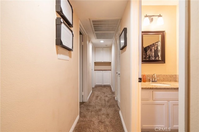 hall with sink and light colored carpet