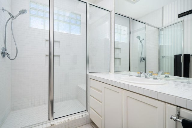 bathroom featuring a shower with shower door and vanity