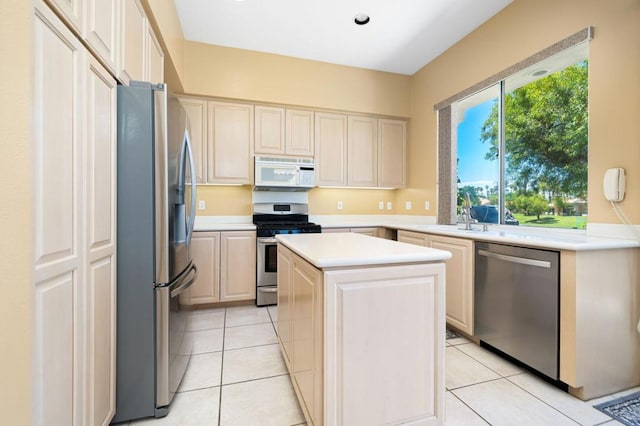 kitchen with light tile patterned floors, stainless steel appliances, a kitchen island, and sink