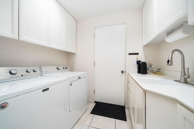 clothes washing area featuring washer and dryer, sink, light tile patterned floors, and cabinets