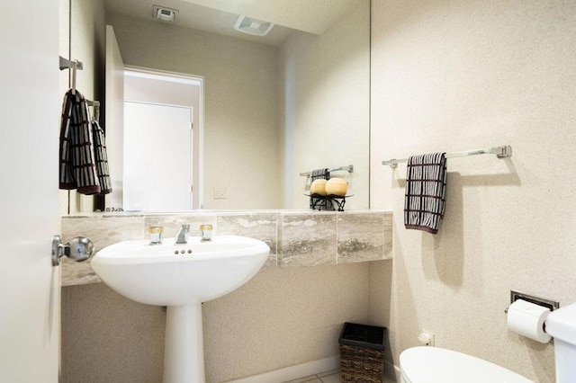 bathroom with decorative backsplash, toilet, and tile patterned flooring