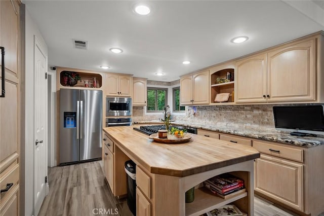 kitchen with a kitchen island, light hardwood / wood-style flooring, stainless steel appliances, light brown cabinetry, and wood counters