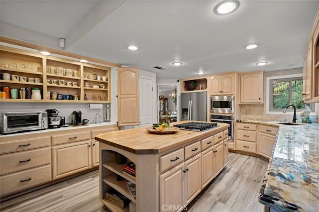 kitchen with light brown cabinets, appliances with stainless steel finishes, a center island, and wooden counters