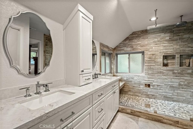 bathroom featuring vaulted ceiling, a tile shower, and vanity