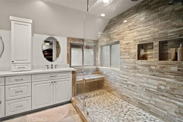 bathroom with a shower with shower door, vanity, and vaulted ceiling