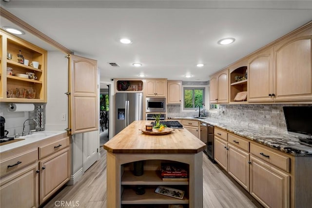 kitchen featuring butcher block counters, stainless steel appliances, light brown cabinets, a kitchen island, and sink