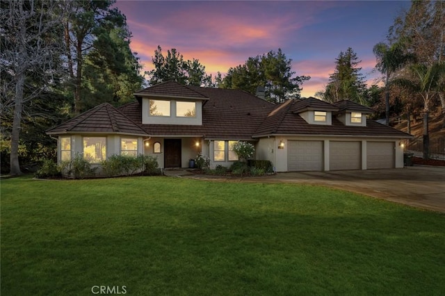 view of front of home with a garage and a lawn