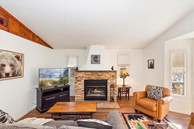 living room featuring wood-type flooring, lofted ceiling, and a fireplace