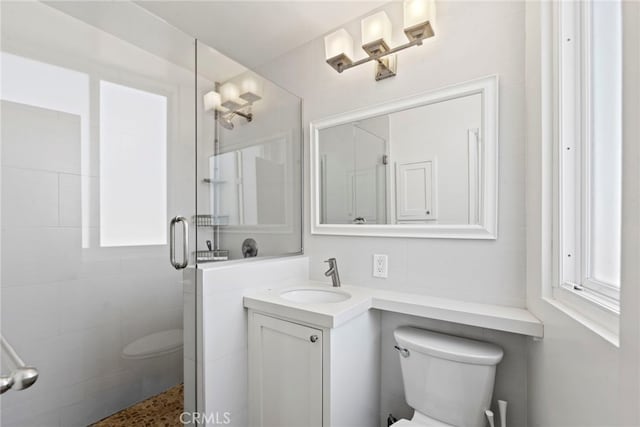 bathroom featuring vanity, a shower with shower door, and toilet